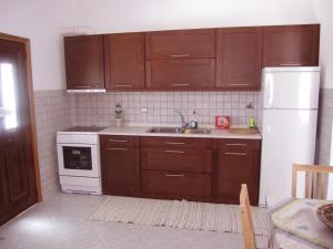 塞里福斯Ariston Apartments的厨房配有木制橱柜和白色冰箱。