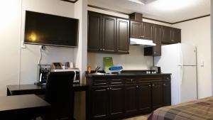 Shaunavon熊窝旅舍的厨房配有黑色橱柜和白色冰箱。