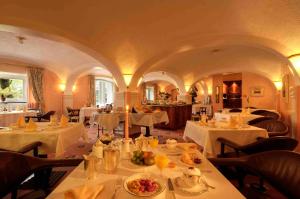 卡斯拉诺Villa Garni Gardenia的餐厅配有白色的桌椅,提供食物