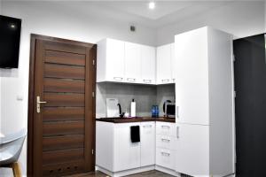 雷布尼克Studio Fibra Dolce的厨房配有白色橱柜和木门。