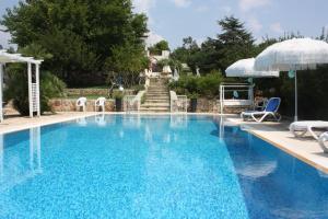 托雷圣乔万尼乌Villa Torre San Giovanni Ugento的一个带椅子和遮阳伞的游泳池