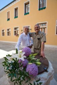 威尼斯艾尔马尔卡通酒店的两个年纪较大的男人站在桌子旁边,一边种着鲜花