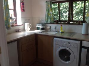 考斯New Stable Cottage的厨房配有洗衣机和水槽