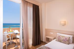 利迈纳里亚Sunray Hotel的酒店客房设有一张床铺、一张桌子和一个阳台。