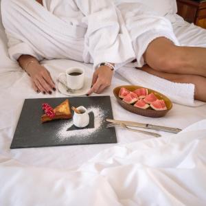 赫尔格达The Oberoi Beach Resort, Sahl Hasheesh的床上的女人,有盘子的食物和一杯咖啡