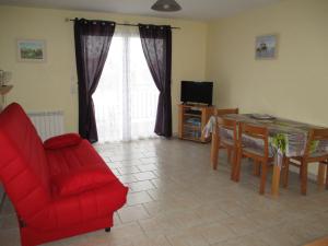 滨海苏拉克Logement Soulac sur mer的客厅配有红色椅子、桌子和电视