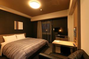 新城市Hotel Route-Inn Shinshiro的酒店客房,配有床和电视
