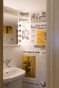 弗里堡阿尔法酒店的设有带水槽的浴室和墙上的报纸