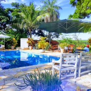 圣代佩德罗拉圣佩德罗旅馆的一个带两把白色椅子和遮阳伞的游泳池
