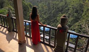 乌布Villa Kalisat Resort的站在阳台上的穿着红色衣服的女人