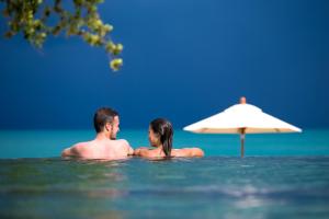 曾蒙海滩海之舞度假酒店的水中一个男人和女人,在雨伞旁边