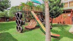 贝拉贝拉Hoogland Spa Resort Bela Bela的棕榈树旁的院子内的游乐场