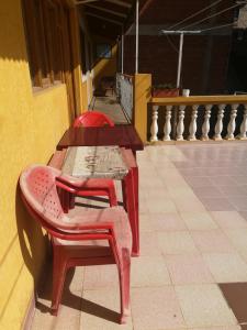 苏克雷Homestay Jorge, Sucre的两张桌子,两把红色椅子坐在大楼旁边