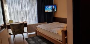 林尼希佳妮朱莉娅酒店的一间卧室配有一张床、一张书桌和一台电视。