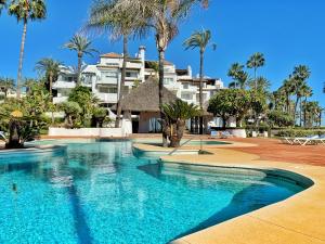 Estepona阿尔卡萨瓦海滩3302公寓的棕榈树酒店前的游泳池