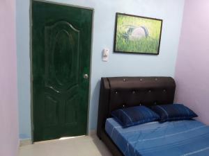 Kampong MerbokDZe Homestay Singkir Genting的隔壁房间的一个绿门,床旁