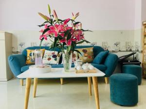 绥和市gau homestay的客厅配有蓝色的沙发和带鲜花的桌子