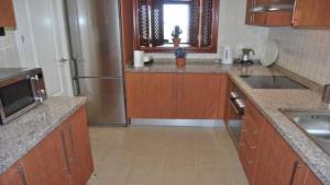 阿尔加德萨Apartamento 6 persona en la Alcaidesa的厨房配有木制橱柜和不锈钢冰箱。