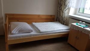 克沃兹科Hotel Śnieżnik的一张带白色床单和枕头的木床
