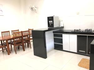 关丹Ana Guest House Jalan Airport Kuantan的厨房配有黑色柜台和桌椅