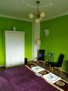 科隆科隆住宿酒店的绿色的客房配有两把椅子和白色的橱柜