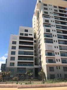 卡萨布兰卡Appartement Casa-marina au 10ème étage的一座高大的白色建筑,前面有棕榈树