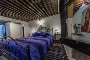 非斯哈拉庭院酒店的一间卧室配有一张带紫色棉被的床