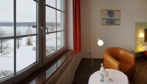 OlbersdorfHotel Haus am See的客房设有桌子、椅子和窗户。