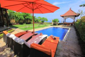 BanjarOcean Beachfront Villa Dini的游泳池旁的红色遮阳伞和椅子