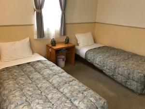 立科町Petit Hotel Kurumi to Milk的客房设有两张床、一张桌子和一个窗户。