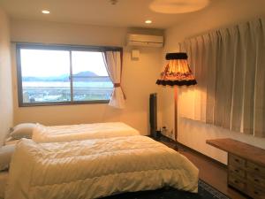 直岛町直岛背包客旅馆的一间卧室设有两张床和大窗户