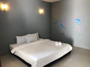 甲米镇红松之家酒店的卧室配有一张铺有白色床单的床和墙上的蝴蝶。