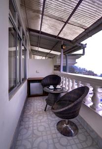 大吉岭怀特雅克酒店的阳台的天井配有2把椅子和1张桌子