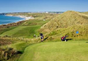 巴利巴宁Ballybunion Holiday Homes No 27的一群人在靠近海洋的高尔夫球场上