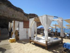 费拉古多Vila Monte Luz的沙滩上的一张床铺,上面有遮阳伞