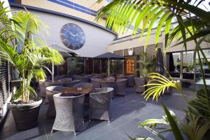 加亚新城索维德Spa和健康中心酒店的一间种有植物和桌子的餐厅,墙上挂着一个钟