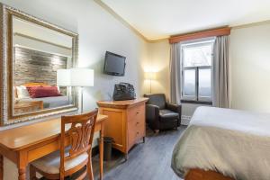 魁北克市贝尔维城堡酒店的酒店客房带一张床、一张书桌和一面镜子