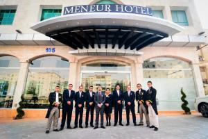 安曼梅内尔酒店的一群穿着西装的男人站在酒店前