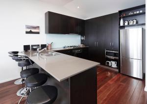 布勒山K2 14号公寓的一间厨房,配有黑色橱柜和一个带酒吧凳的厨房岛