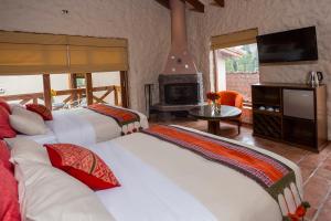 乌鲁班巴Intiterra Apart Hotel Villas的带三张床和壁炉的客房