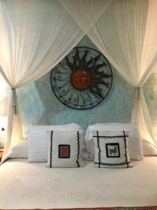 萨尤利塔Casa Juanita的一张带白色枕头的床和墙上的时钟