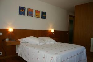 艾斯特拉达Casa rural A Mimoseira的一间卧室配有一张床铺,墙上挂着两盏灯