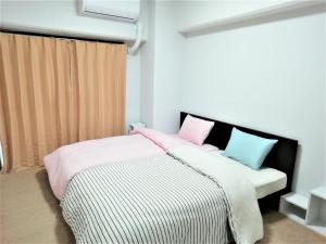 冈山Near Tram Apartment Okayama的一间卧室配有带粉红色和蓝色枕头的床