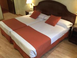 布尔戈斯科登酒店的一间卧室配有两张带橙色和白色床单的床