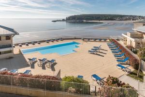 克罗宗Résidence Pierre & Vacances Cap-Morgat的享有带椅子的海滩和游泳池的景色