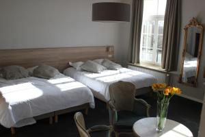 布鲁日马累洛德韦克酒店的一间卧室设有两张床和一张花瓶桌子。