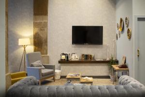 马德里卡门广场小宫殿酒店的客厅配有沙发和墙上的电视