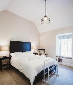 圣安德鲁斯Orchard Cottage的卧室配有一张白色大床和一把椅子