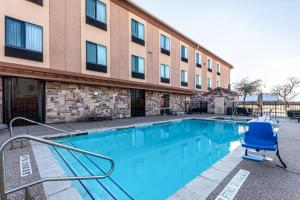矿泉井城Red Lion Inn & Suites Mineral Wells的大楼前带蓝色椅子的游泳池