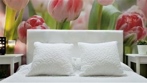 阿罗纳Home Sweet Home的一张带两个枕头和粉红色郁金香的白色床